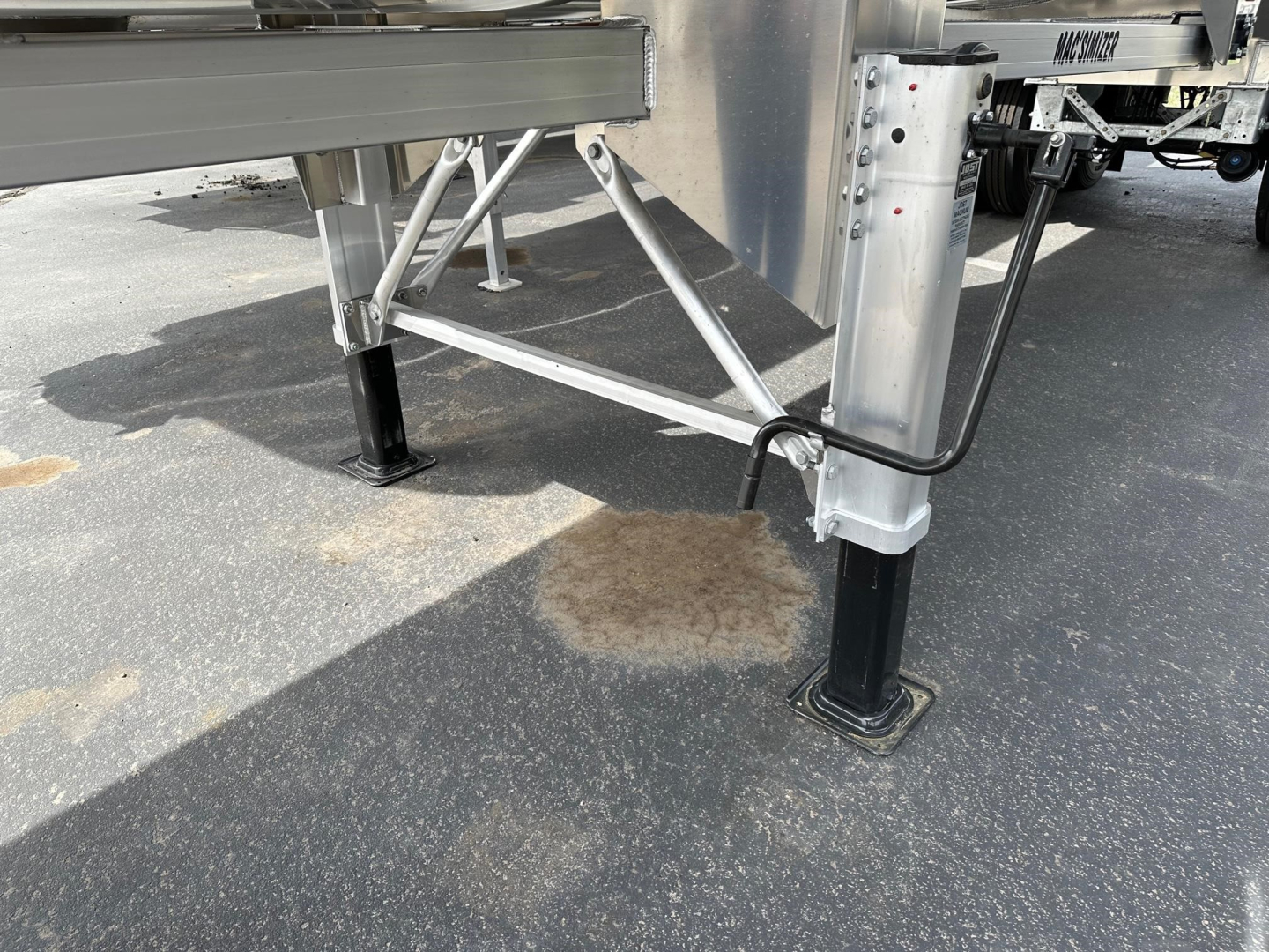 Dump trailer leg and support area with stabilizers and hydraulic lines visible under the chassis.