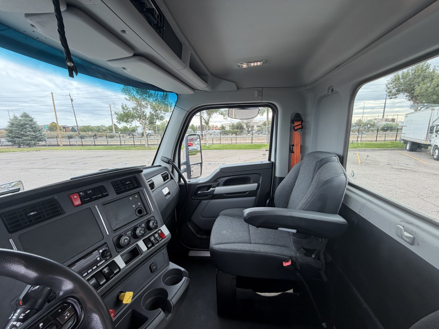 Kenworth T880 cab interior showing steering wheel, dashboard, and passenger seat with windows; part of the cabin visible.