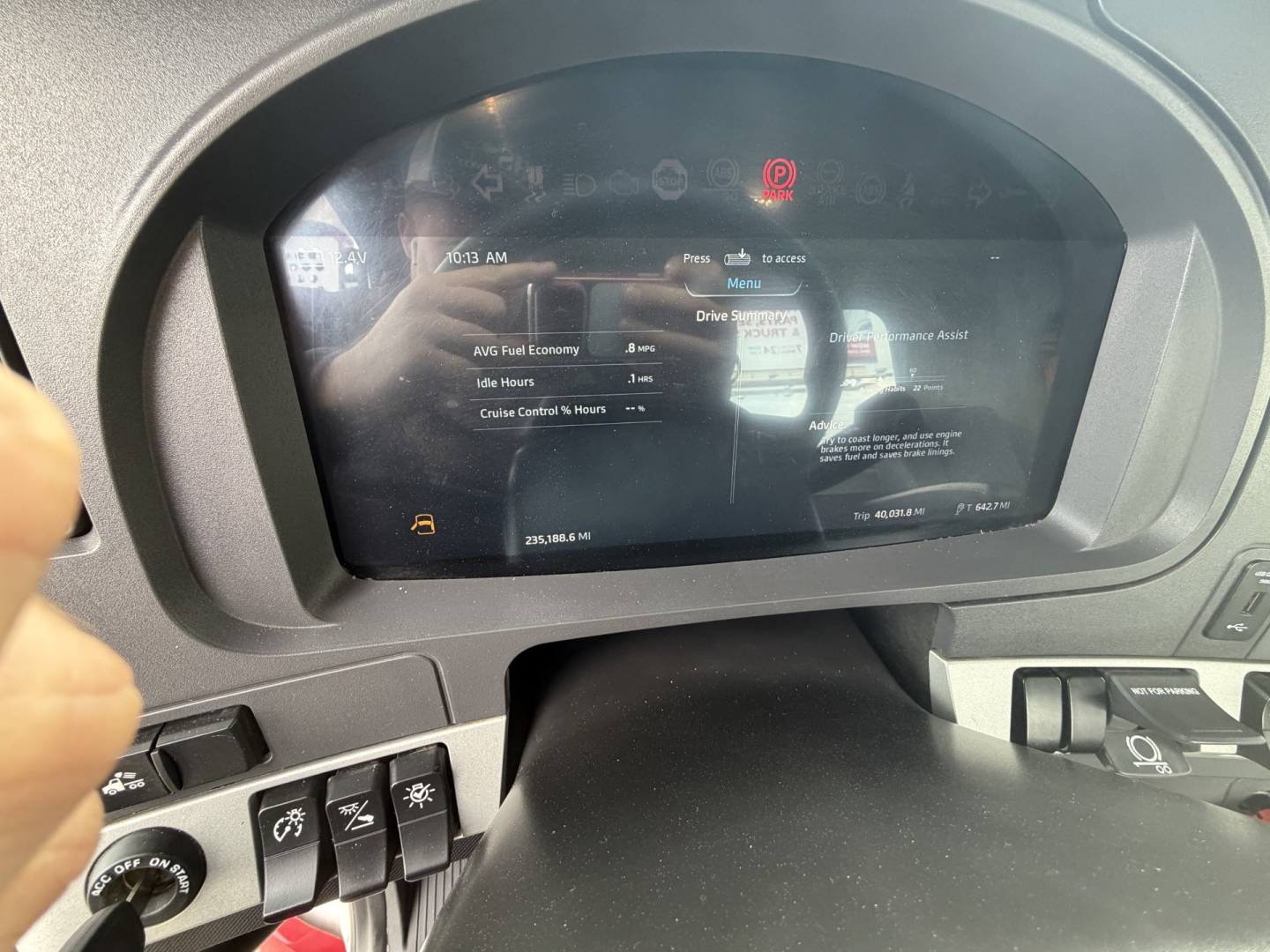 Dashboard display in a 2023 Kenworth T880 showing Drive Information menu and warning icons with reflections on the screen.