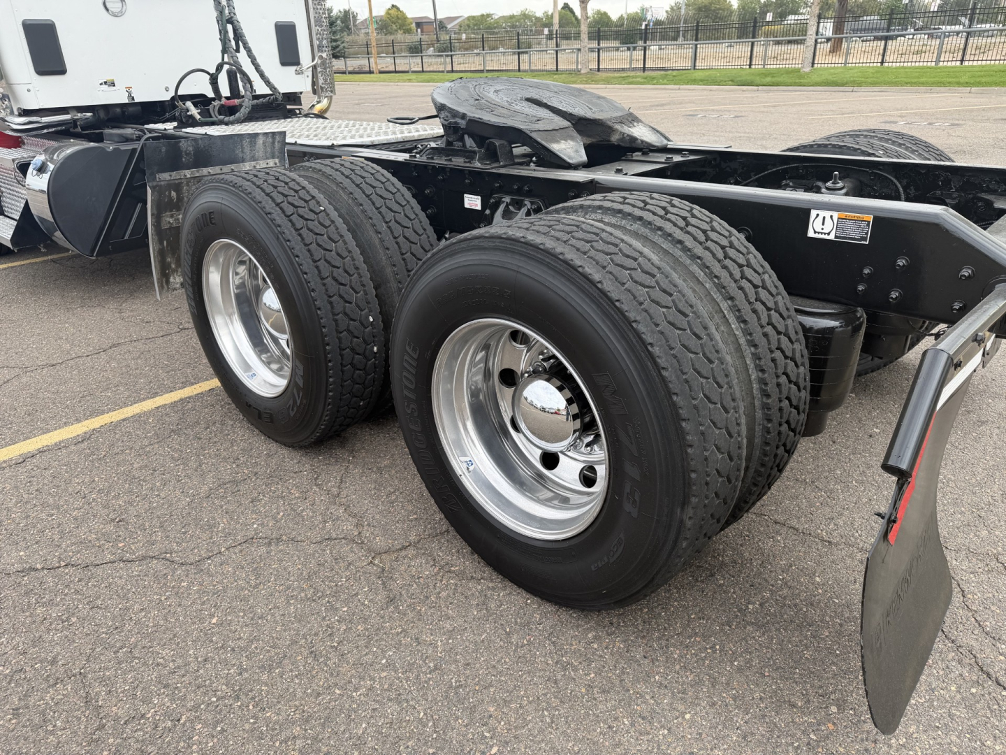 Kenworth T880 chassis showing dual rear axles with large tires and chrome wheels; portion of cab and frame visible.