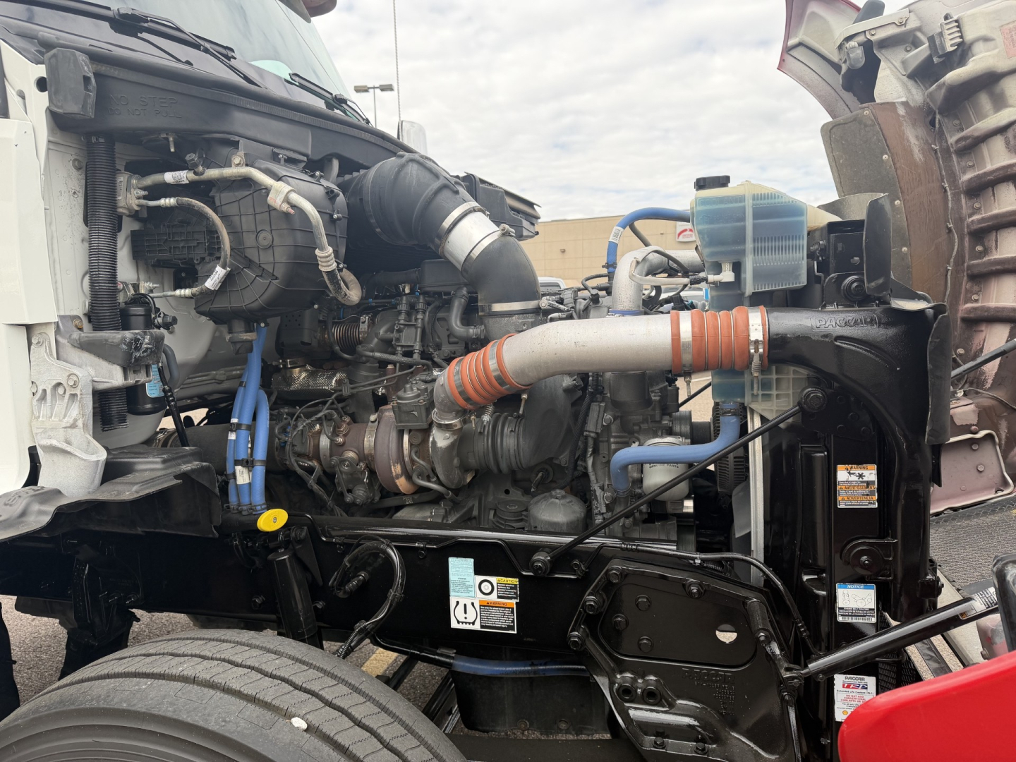 Kenworth T880 engine bay shown with view of turbocharger, intake piping, coolant reservoir, and hydraulic lines.