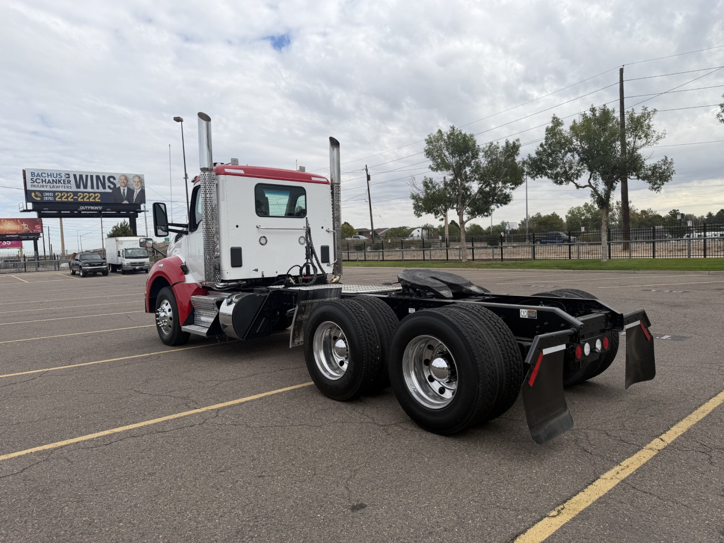 Kenworth T880 daycab tractor rear view showing dual rear axles with mudflaps and wheel mudguards, red/white cab, no trailer attached.
