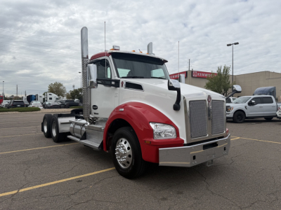Kenworth T880 conventional daycab truck in white and red, front left side view with chrome grille and dual exhaust stacks.