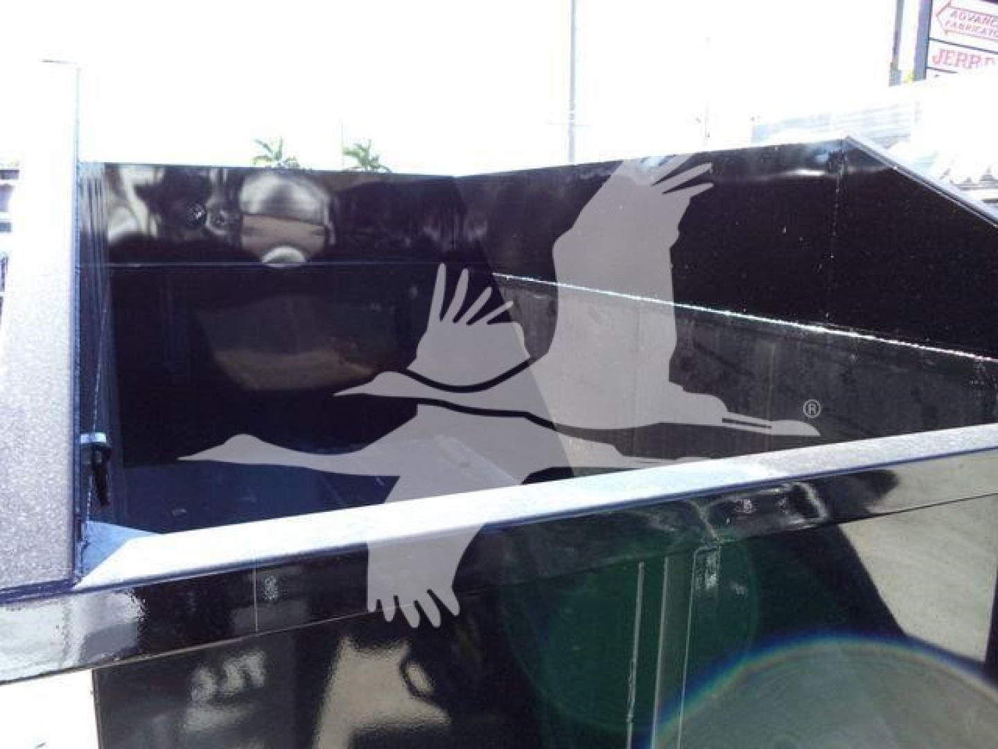 Dump trailer side panel of a 2020 Peterbilt 337 rolloff truck showing reflective black surface and metal trim.