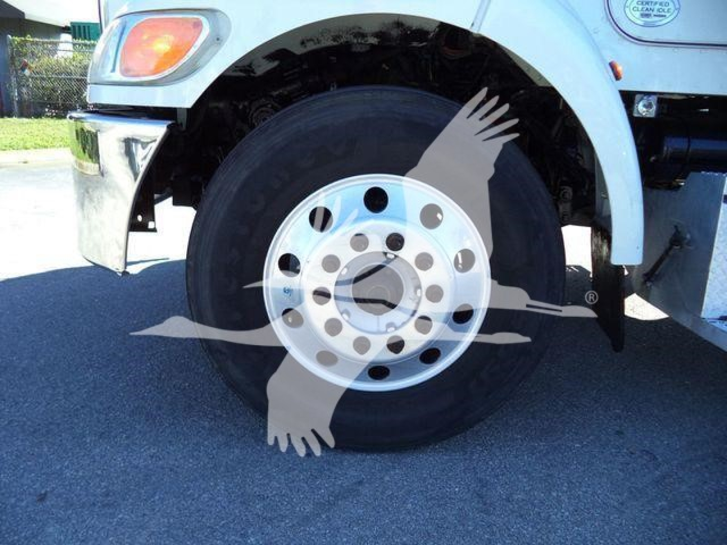 Peterbilt 337 front wheel well showing front axle and hub, partial bumper with chrome, riveted white fender, and wheel with multi-hole rim.