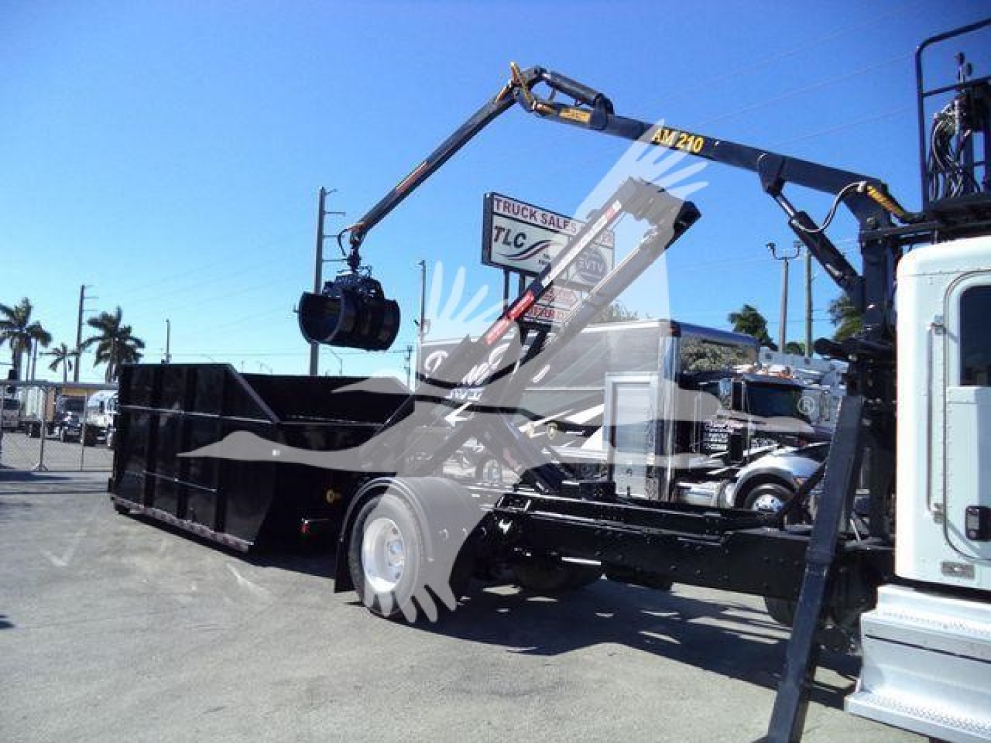 Peterbilt 337 roll-off truck in yard with hydraulic crane, bed extended, front cab visible on right, stock and VIN tags not legible.