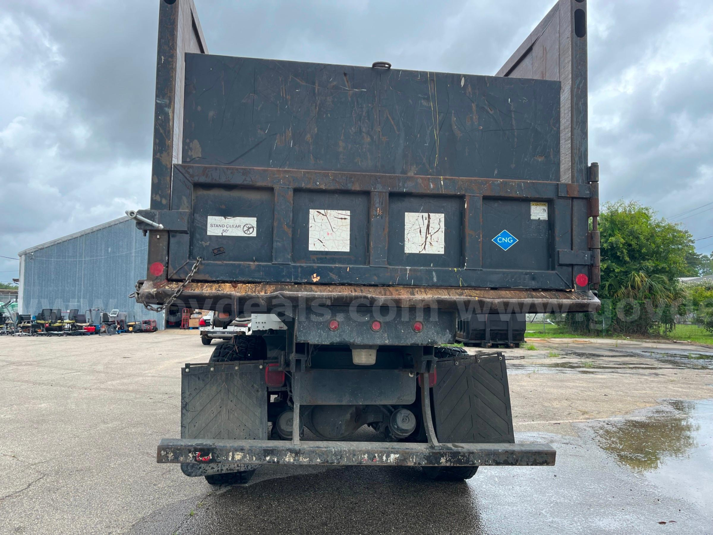 Rear view of 2013 Freightliner M2 112 dump truck showing cargo bed and bumper with hydraulic components and mud flaps.