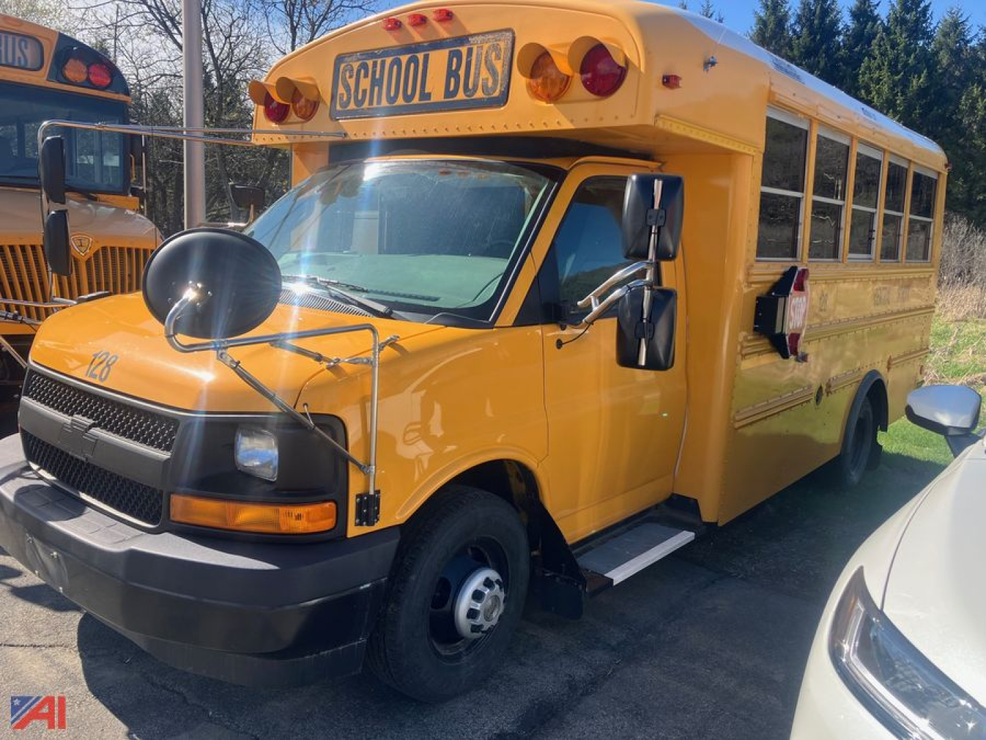 Yellow 2018 Chevrolet G4500 school bus viewed from front-left angle with side mirrors and large stop arm, 'SCHOOL BUS' sign atop windshield, black bumper, and wheel wells.