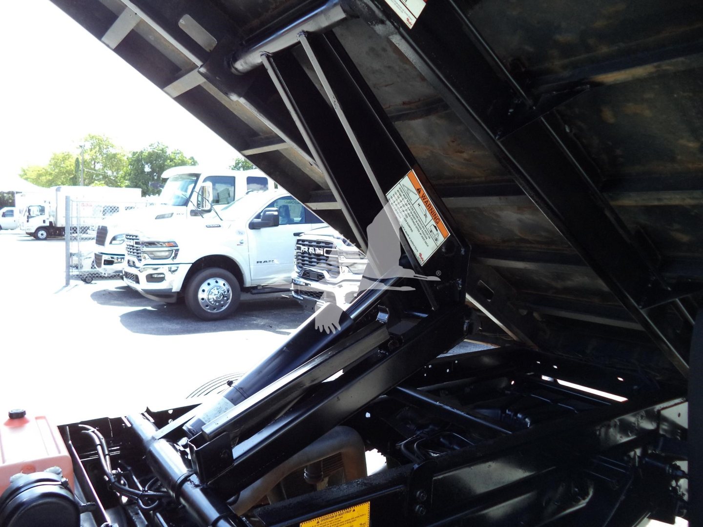 Ford F-450 truck dump bed in elevated position showing hydraulic lift and engine bay area.