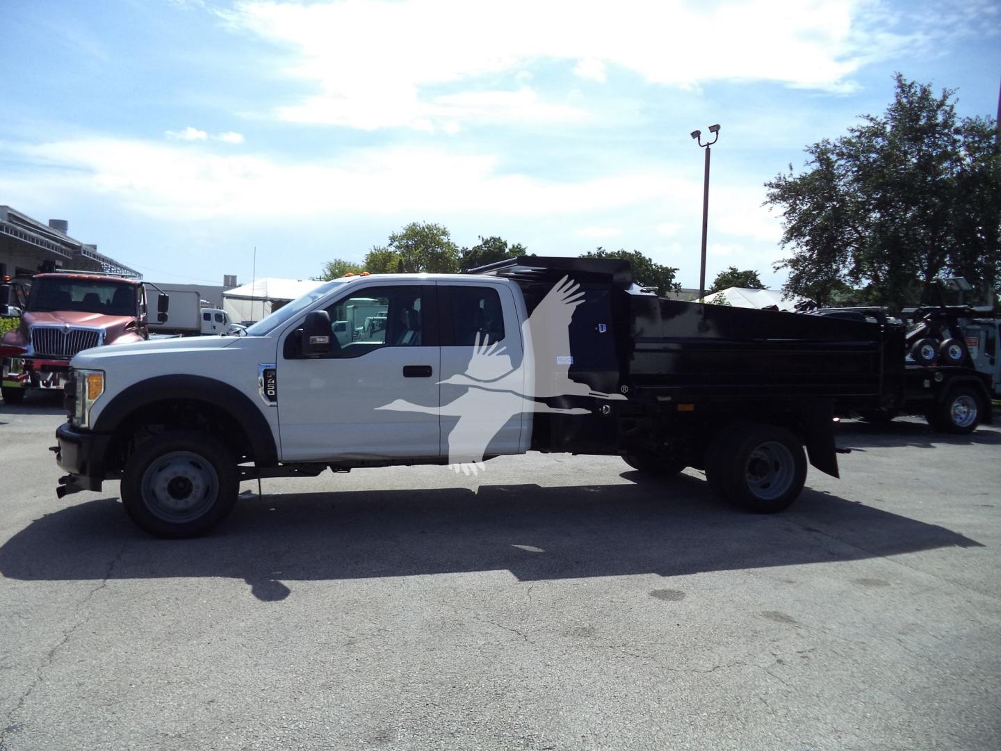 Ford F-450 pickup truck in white cab, black dump bed, side view showing length and dual rear wheels