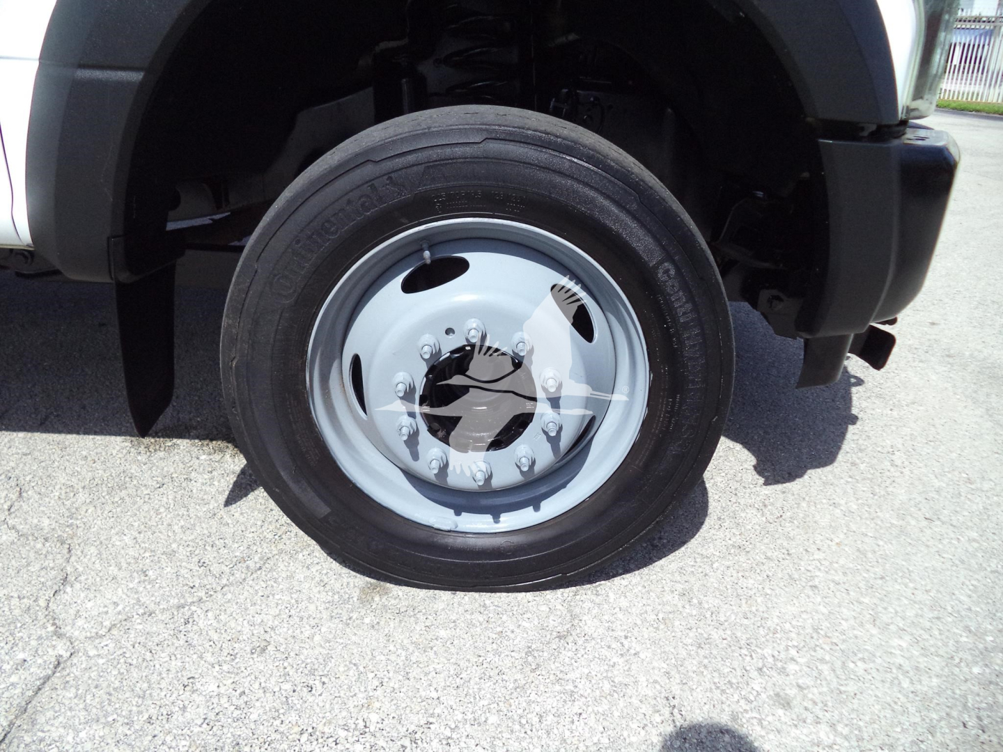 Ford F-450 front wheel and fender showing steel wheel with lug nuts and tire.