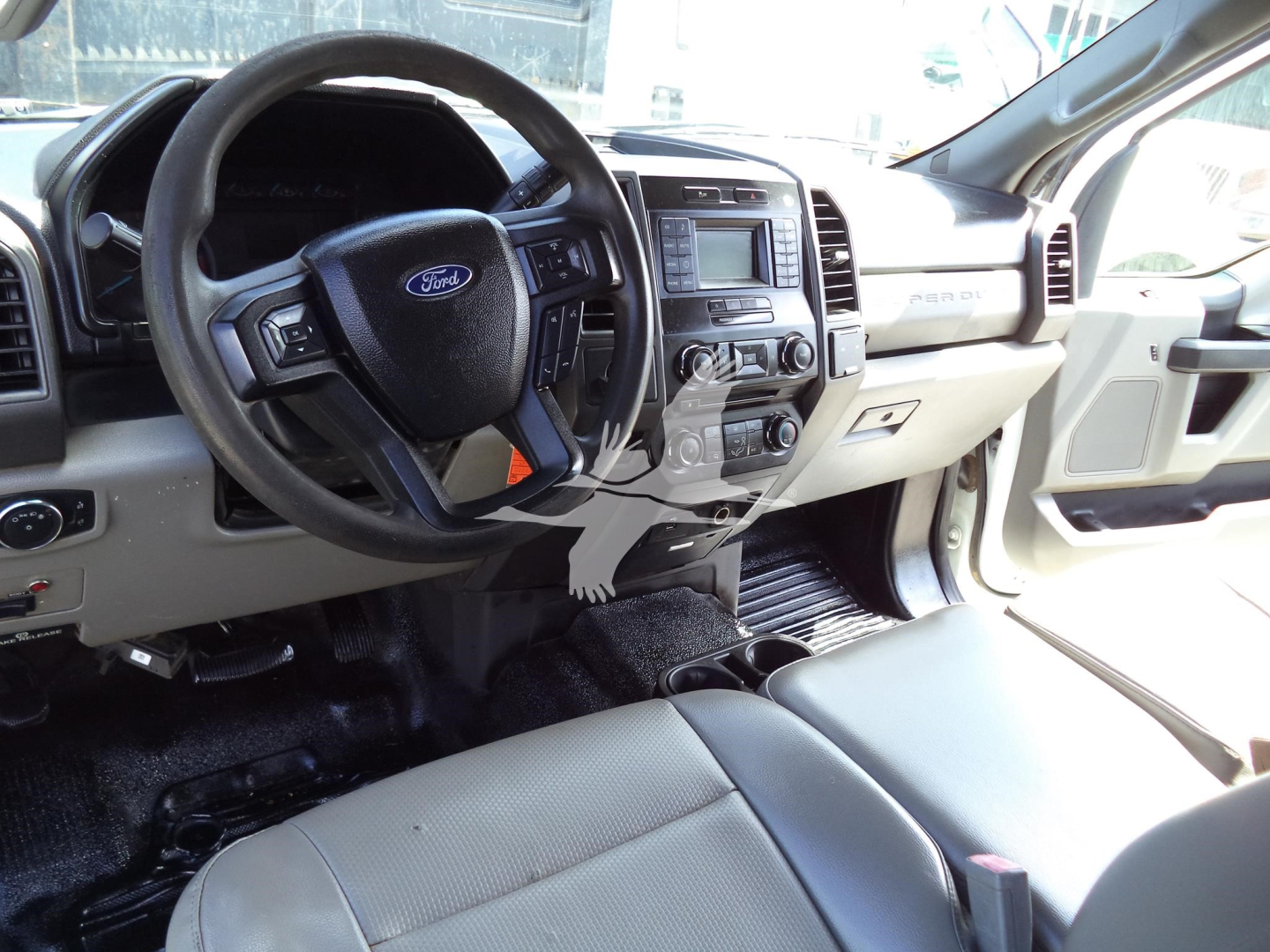 Ford F-450 interior cabin view showing steering wheel with Ford logo, center console, and front seats. Dashboard and infotainment system visible.