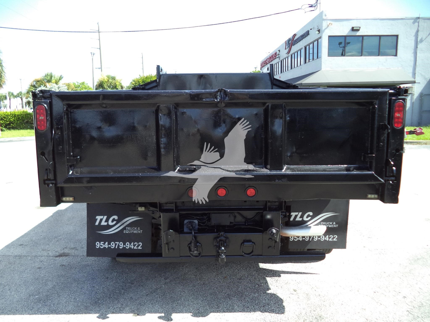 Back view of a black dump truck bed on a 2017 Ford F-450 XL showing tailgate, rear lights, hitch, and TLC dealer plates.