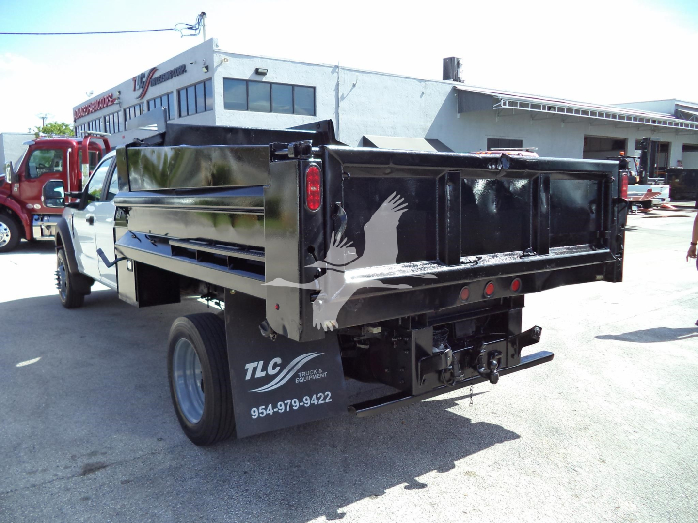 Truck bed of a 2017 Ford F450 XL dump with black dump body, rear view showing TLC Industrial Equipment logo and phone number on the mudflap.