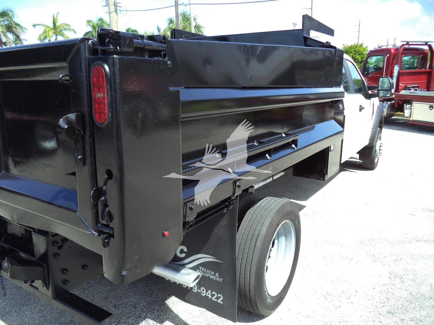 Dump truck bed of a 2017 Ford F450 XL with black dump side panel and white cab visible; rear wheel and tail light visible.