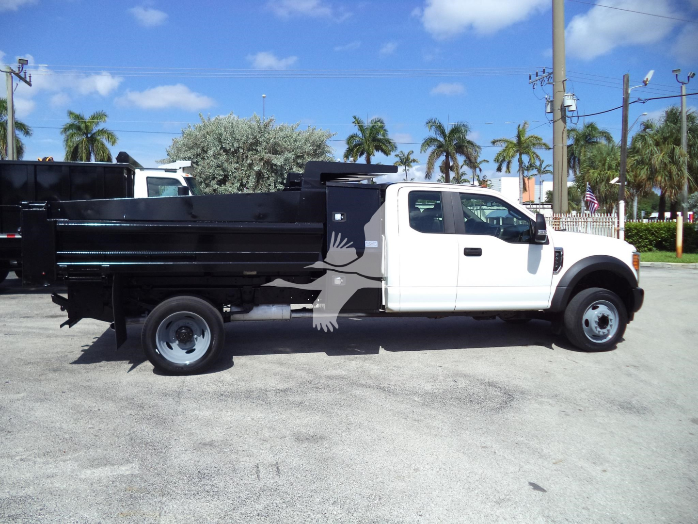 Truck side view showing a white 2017 Ford F450 XL dump truck with a black dump bed.