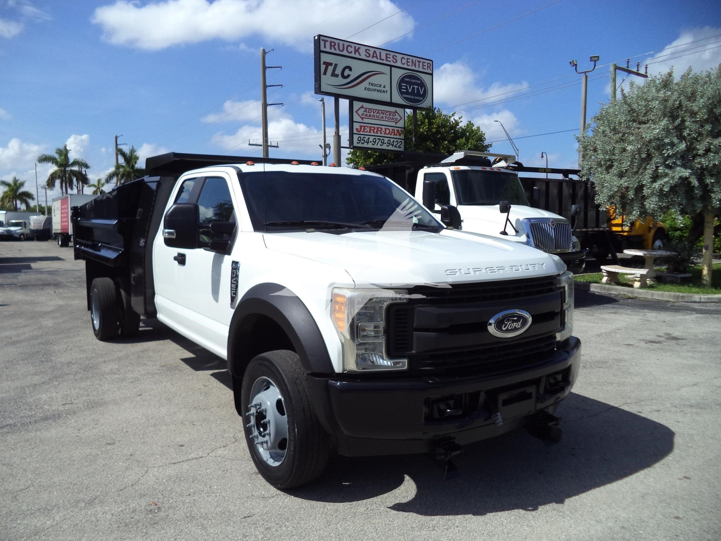 Ford F-450 XL dump truck front-left view with white cab and black grille showing Ford emblem and large dual rear wheels.
