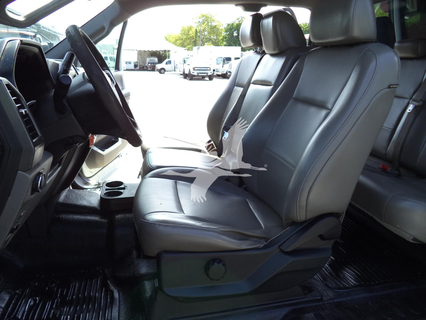 Ford F-450 interior front seats view with steering wheel, dashboard, and center console in XL trim; black leather-like seats; plastic flooring.