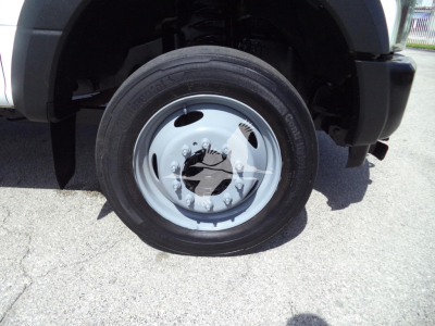 Ford F-450 front wheel and fender showing steel wheel with lug nuts and tire.