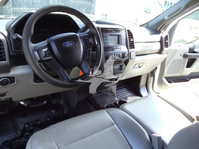 Ford F-450 interior cabin view showing steering wheel with Ford logo, center console, and front seats. Dashboard and infotainment system visible.