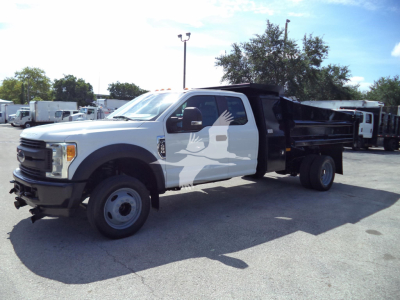 Ford F-450 XL dump truck in service showing front-left angle with open cab door and dumped bed.