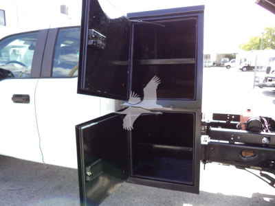 Ford F-450 truck with an open rear storage locker showing empty compartments and black exterior.