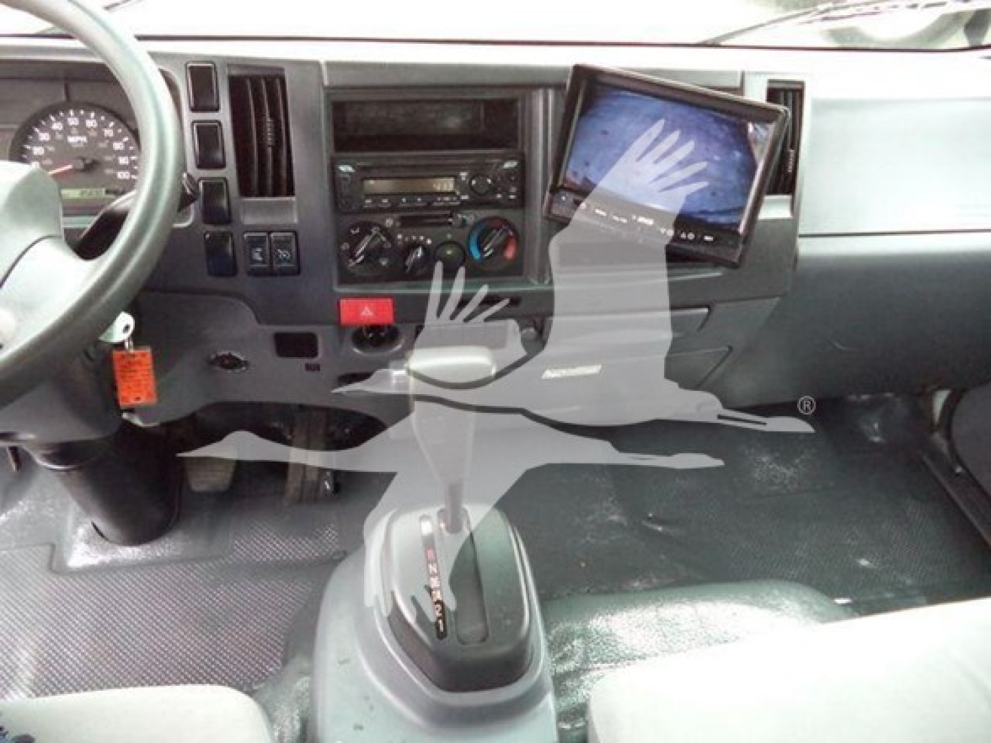 Isuzu NPR HD cab interior showing steering wheel, dashboard, center console with radio, climate controls, and a mounted tablet display.