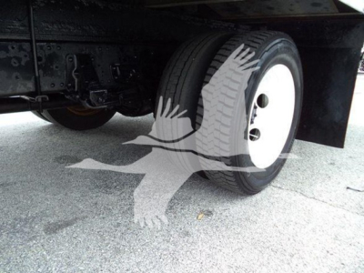 Isuzu NPR HD undercarriage showing front wheel with white rim and dual tires, underbody frame and suspension components visible.