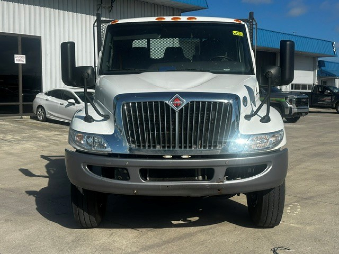 Front view of a white International MV607 rollback truck showing large grille, dual side mirrors, and headlights.