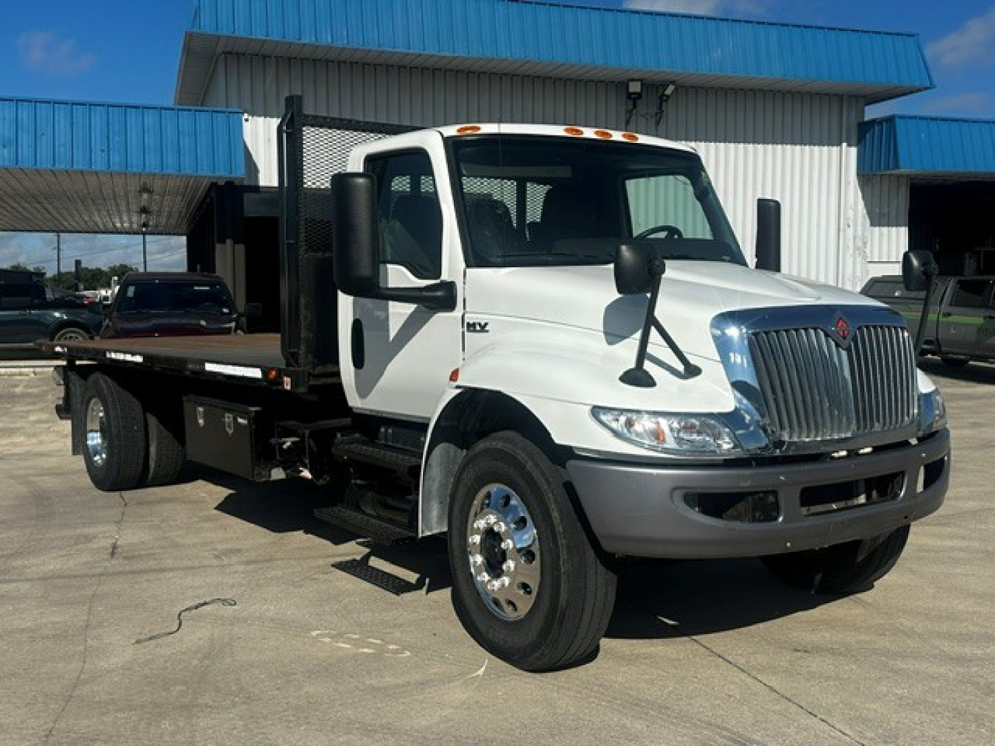 White International MV Series rollback tow truck with flatbed, front grille, mirrors, and side steps visible; no plate text legible.