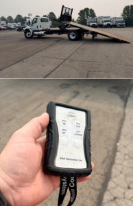 Truck with a rollback bed extended low on the ground and a handheld remote control showing STOP/START, RAISE IN/OUT, BWD UP/DOWN labels for a 2020 International MV607.