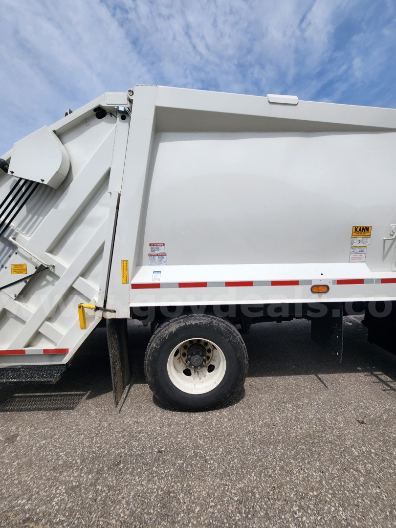 Truck side view showing white Freightliner M2 106 dump body with wheel and reflective stripes