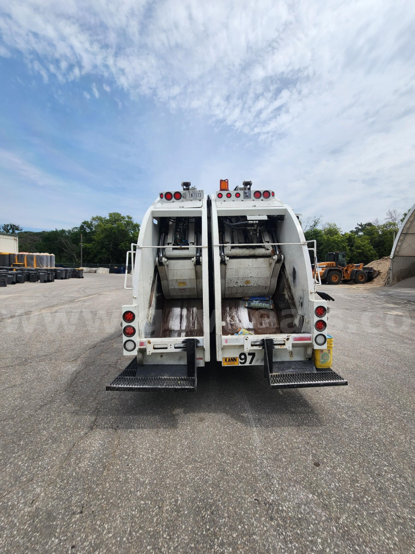 Rear view of a 2021 Freightliner M2 106 garbage truck showing two rear compactor units and taillights.