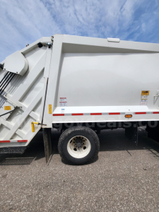 Truck side view showing white Freightliner M2 106 dump body with wheel and reflective stripes