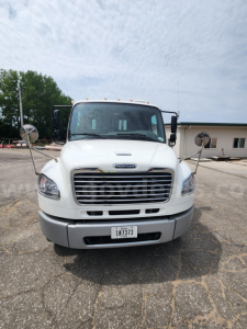 Front view of white Freightliner M2 106 truck showing grille, bumper, headlights, windshield, and side mirrors.