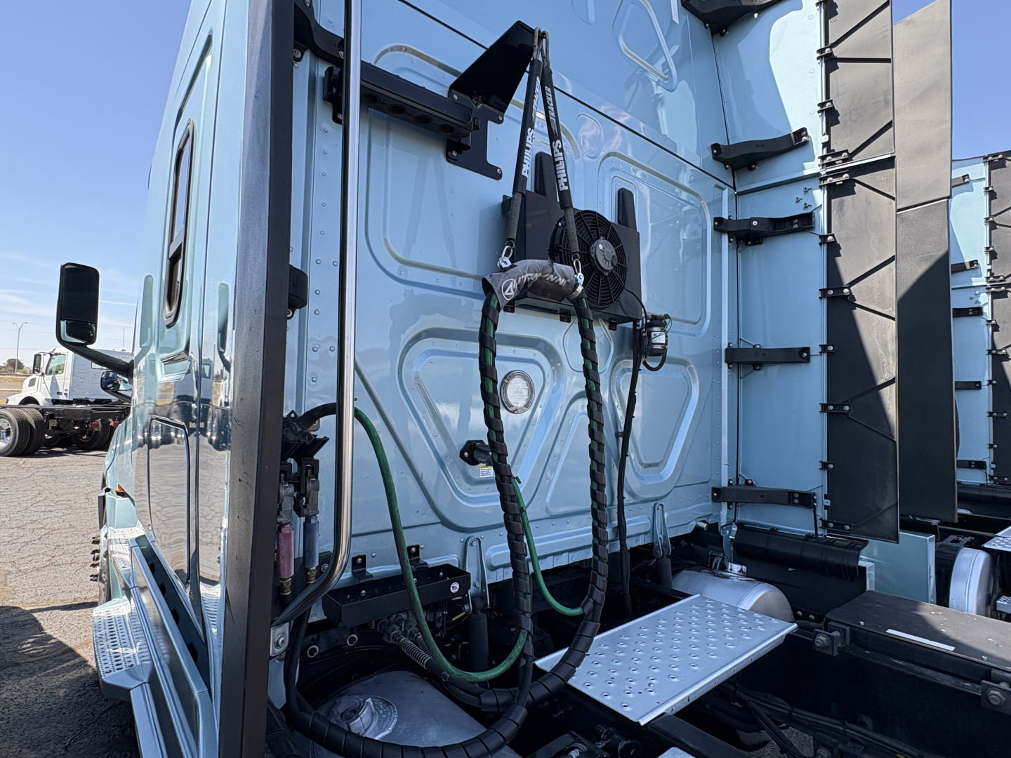 Truck cab interior side view showing air lines and step with metal tread on Freightliner Cascadia 126, rear cab area air hoses and mounting brackets visible.