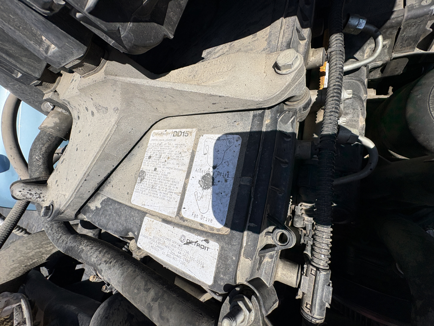 Truck engine bay showing label stickers and wiring harnesses on a Freightliner Cascadia 126 engine compartment.