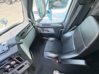 Cab interior of a Freightliner Cascadia 126 truck showing black leather seat, driver-side door area, dashboard gauges and controls.