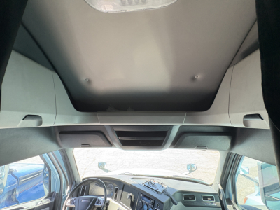 Cab interior of a 2023 Freightliner Cascadia 126 tractor showing dashboard, steering wheel, overhead console, and sun visor; heater/AC vents visible.