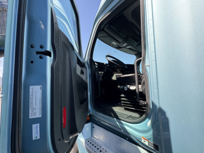 Cab interior of a Freightliner Cascadia 126 truck with door open, steering wheel, driver seat, and dashboard visible.