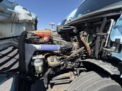 Freightliner Cascadia 126 engine bay showing diesel fuel filter and various hoses and wiring harnesses.
