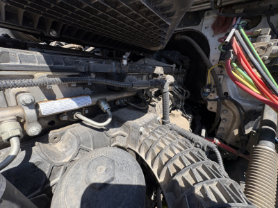 Engine bay of a Freightliner Cascadia 126 showing intake manifold, wiring harness, and visible labels.
