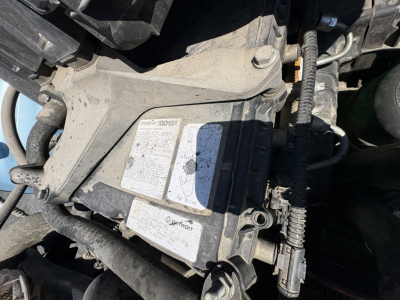 Truck engine bay showing label stickers and wiring harnesses on a Freightliner Cascadia 126 engine compartment.