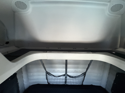 Freightliner Cascadia 126 sleeper cab interior photo showing rear cargo area with netted storage and curved sleeper wall.