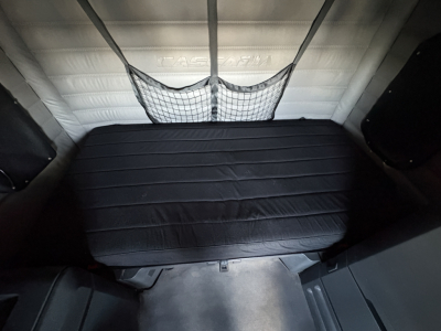  Freightliner Cascadia 126 sleeper cab interior cargo area with net storage and padded backrest.