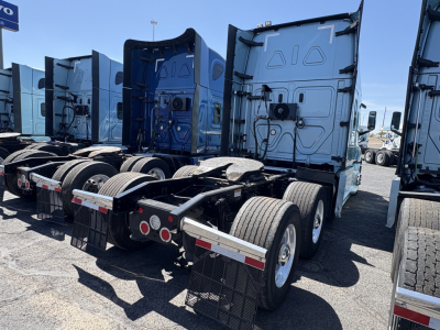 Freightliner Cascadia 126 tractor rear view showing dual rear axles, fifth wheel, and mud flaps in a truck lot.