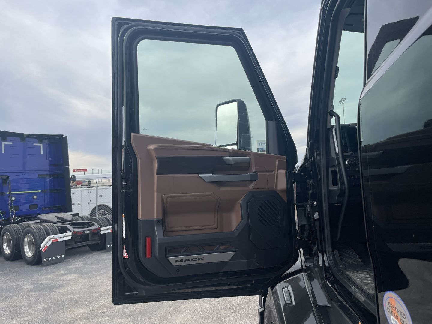 Truck cab door interior panel with Mack logo and window, view into open door of 2026 Mack PR64T76H sleeper truck