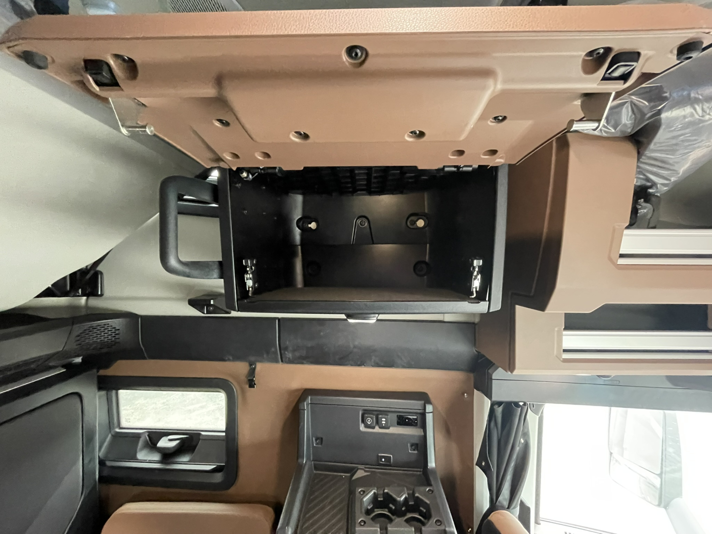 Cab interior of a 2026 Mack PR64T76H truck showing storage compartments and control panels in tan and black.