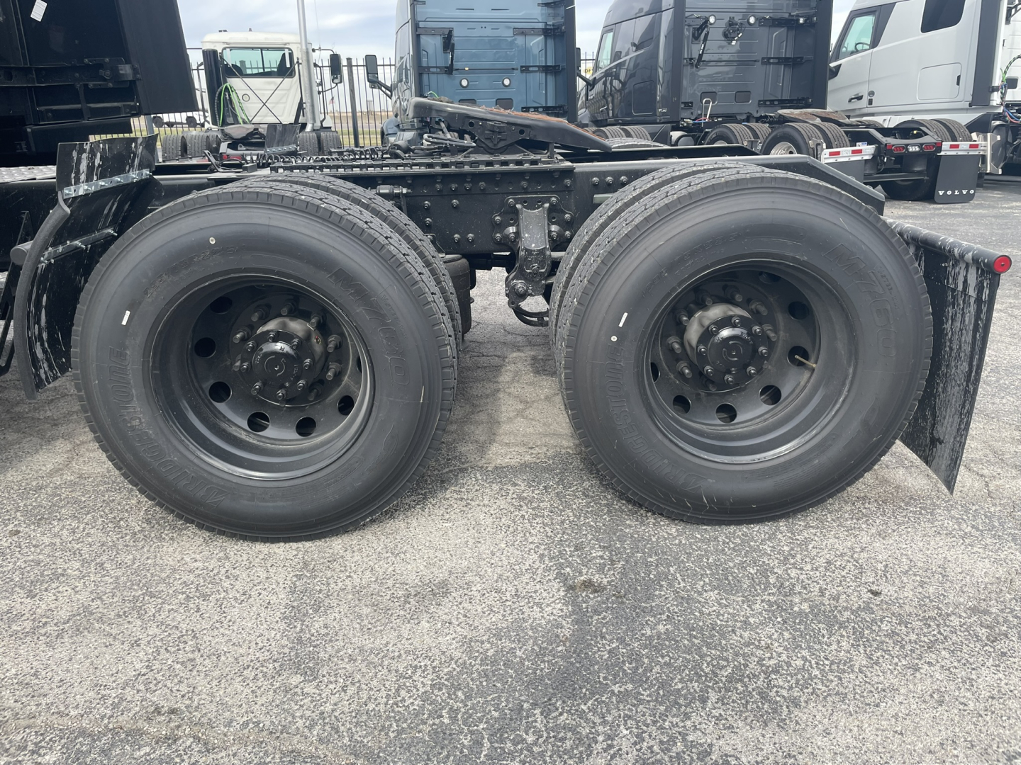 dual rear axles of a Mack PR64T76H truck showing two black wheels and tires with suspension and frame components.