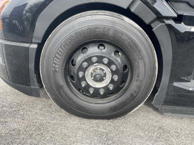 Bridgestone tire mounted on the front wheel of a 2026 Mack PR64T76H sleeper tractor, visible wheel studs and hub; tire brand and tread area clear.